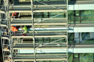 alto salire edificio sotto costruzione. installazione di bicchiere facciata pannelli su un' rinforzata calcestruzzo struttura. foto