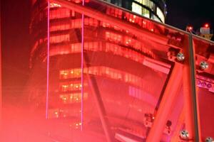 frammento di il bicchiere facciata di un' moderno aziendale edificio a notte. moderno bicchiere ufficio nel città. grande raggiante finestre nel moderno ufficio edifici a notte, nel righe di finestre leggero brilla. foto