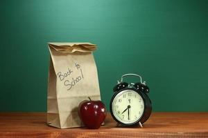 pranzo scolastico, mela e orologio sulla scrivania a scuola foto