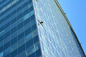 bicchiere edificio con trasparente facciata di il edificio e blu cielo. strutturale bicchiere parete riflettendo blu cielo. astratto moderno architettura frammento. contemporaneo architettonico sfondo. foto