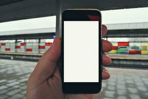 mano Tenere smartphone con metropolitana stazione sfondo foto