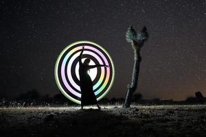 persona dipinta di luce nel deserto sotto il cielo notturno foto