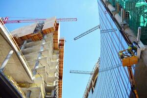 alto salire edificio sotto costruzione. installazione di bicchiere facciata pannelli su un' rinforzata calcestruzzo struttura. foto