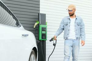 uomo in piedi di il suo elettrico auto foto