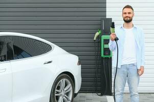 uomo in piedi di il suo elettrico auto foto