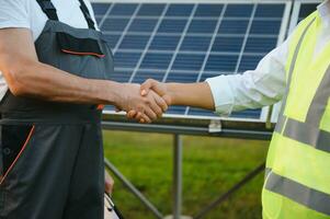 vicino su uomo d'affari e ingegneri tremante mani dopo discutere installare solare pannelli su case sotto costruzione, rinnovabile energia per Residenziale foto