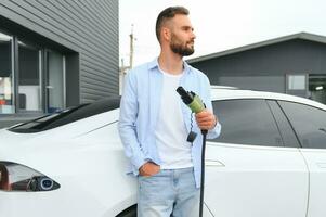 uomo in piedi di il suo elettrico auto foto