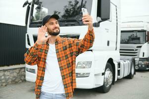 ritratto di giovane barbuto uomo in piedi di il suo camion. professionale camion autista in piedi di semi camion veicolo. foto