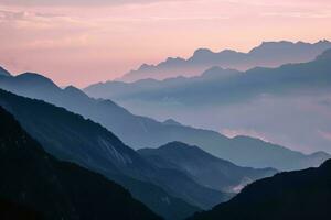 ai generato un' mozzafiato Immagine di stratificato montagne velato nel nebbia, sotto il morbido splendore di un' tranquillo tramonto. il smorzato colori e dolce leggero creare un' tranquillo, calmo e calmante foto