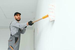 giovane lavoratore pittura parete nel camera. foto