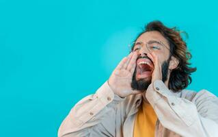 uomo urlando forte chiamata Attenzione con mani piace megafono isolato su blu studio sfondo foto