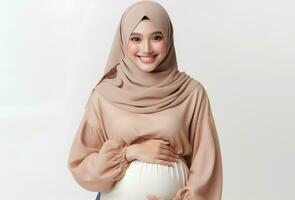 ai generato asiatico donna nel hijab con posa Tenere incinta pancia e sorridente facciale espressione isolato bianca sfondo foto