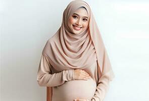 ai generato asiatico donna nel hijab con posa Tenere incinta pancia e sorridente facciale espressione isolato bianca sfondo foto
