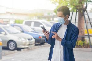 l'uomo indossa la maschera per il viso utilizzando lo smartphone mobile foto