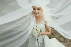 il sposa è seduta su un' roccia alto nel il montagne Il prossimo per un' grande pietra. nozze vestire. il sposa sotto il velo foto