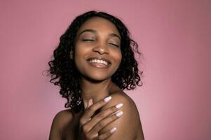 cura della pelle e bellezza concetto. africano americano sorridente donna isolato su rosa sfondo foto