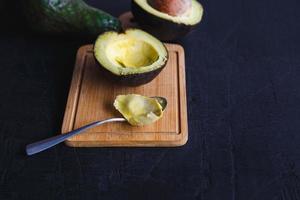 frutto di avocado tagliato a metà su fondo di legno nero foto