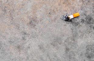 il mozzicone di sigaretta lasciato cadere sul pavimento di cemento foto