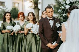 bellissimo nozze coppia su il nozze autunno cerimonia. il il giro arco è decorato con bianca fiori foto