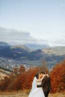 amorevole coppia nel il montagne. matrimoni nel il montagne. indietro Visualizza di il sposini coppia in piedi su il montagne e godendo il paesaggio. foto