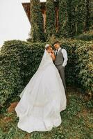 sposa e sposo nel il giardino tra verde. reale nozze concetto. elegante della sposa vestito con un' lungo treno. tenerezza e calma. ritratto fotografia foto