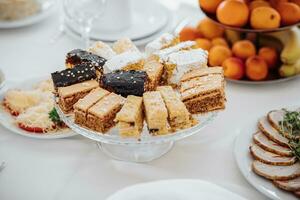 solenne banchetto. un' buffet tavolo con un' lotto di delizioso spuntini. dolci su un' bianca tovaglia. formaggio spuntini. preparazione per il celebrazione foto