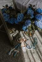 un' Perfetto composizione di il dettagli di il sposa. blu ortensie su il sfondo di nozze anelli e della sposa scarpe. riflessione nel il specchio. foto