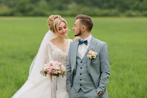 il Novelli sposi In piedi nel il campo e Guarda a ogni Altro. il sposa è Tenere un' mazzo. nozze nel natura. ritratto di il sposa e sposo. elegante sposo foto