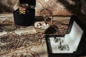 Accessori per il quello dello sposo nozze. un' oro guarda, oro anelli, argento gemelli su un' d'oro tovaglia. Uomini moda e stile foto