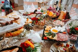 buffet tavolo a il nozze. un assortimento di spuntini su bianca piatti in piedi su un' in stile ucraino tovaglia. banchetto servizio. cibo, spuntini con formaggio, prosciutto, prosciutto e verdi. foto