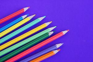 Multi colore matite pastelli su viola sfondo con copia spazio per aggiungendo testo. concetto, formazione scolastica materiali. arte disegno e pittura attrezzatura. foto