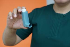 vicino su del paziente mano detiene asma inalatore. concetto, Salute cura. farmaceutico prodotti per trattamento sintomi di asma o cod. uso sotto prescrizione. Salute cura dispositivo a casa. foto