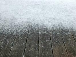 il primo neve abbattere su il di legno pavimento di il terrazza, inverno sfondo foto
