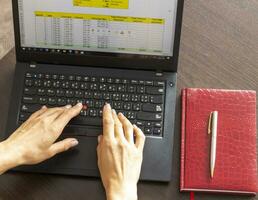 tiro di un' donna Lavorando su il il computer portatile mostrando un eccellere foglio su il schermo con banca prestito ammortamento tavolo. contabilità foto