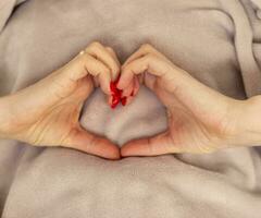 donna detiene sua mani nel il forma di il cuore come un' simbolo di amore. san valentino giorno foto