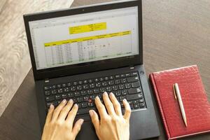 tiro di un' donna Lavorando su il il computer portatile mostrando un eccellere foglio su il schermo con banca prestito ammortamento tavolo. finanza foto