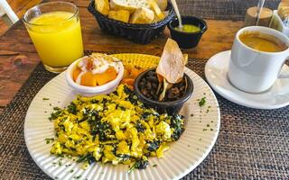 prima colazione strapazzate uova spinaci frutta patate bene disposte su piatto. foto