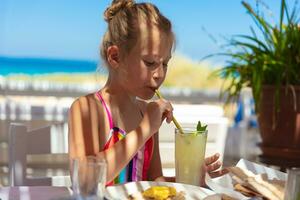 carino poco ragazza potabile succo su il spiaggia foto