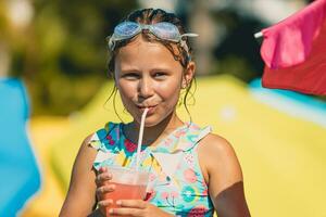 poco ragazza potabile cocktail su il spiaggia foto