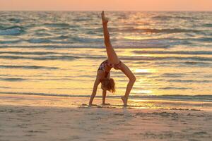 adolescente ragazza fare yoga su il spiaggia foto