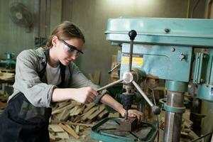 femmina falegname indossare protettivo sicurezza bicchieri e utilizzando elettrico opera su un' Di legno. artista o mobilia progettista Lavorando su un' Prodotto idea nel un' officina. foto