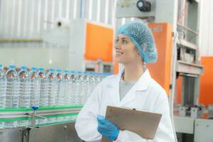 giovane contento donna lavoratore nel fabbrica controllo acqua galloni prima spedizione. foto