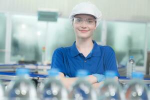 giovane contento donna lavoratore nel fabbrica controllo acqua galloni prima spedizione. foto