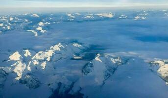 ai generato aereo Visualizza di Alpi montagna gamma con neve e blu cielo. foto