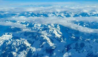 ai generato aereo Visualizza di Alpi montagna gamma con neve e blu cielo. foto