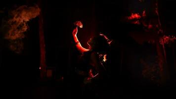 il silhouette di un' femmina ballerino Tenere scintillante gioielleria e guardare acuto nel il buio con fuoco ardente nel il sfondo foto