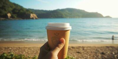 ai generato un' persona mano Tenere un' carta caffè tazza con spiaggia Visualizza. generativo ai foto