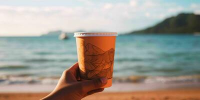 ai generato un' persona mano Tenere un' carta caffè tazza con spiaggia Visualizza. generativo ai foto