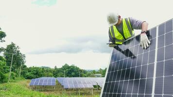 asiatico uomo ingegnere utilizzando digitale tavoletta mantenimento solare cellula pannelli Lavorando all'aperto su ecologico solare azienda agricola costruzione. foto