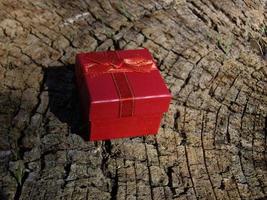 la confezione regalo rossa giace su un ceppo d'albero foto